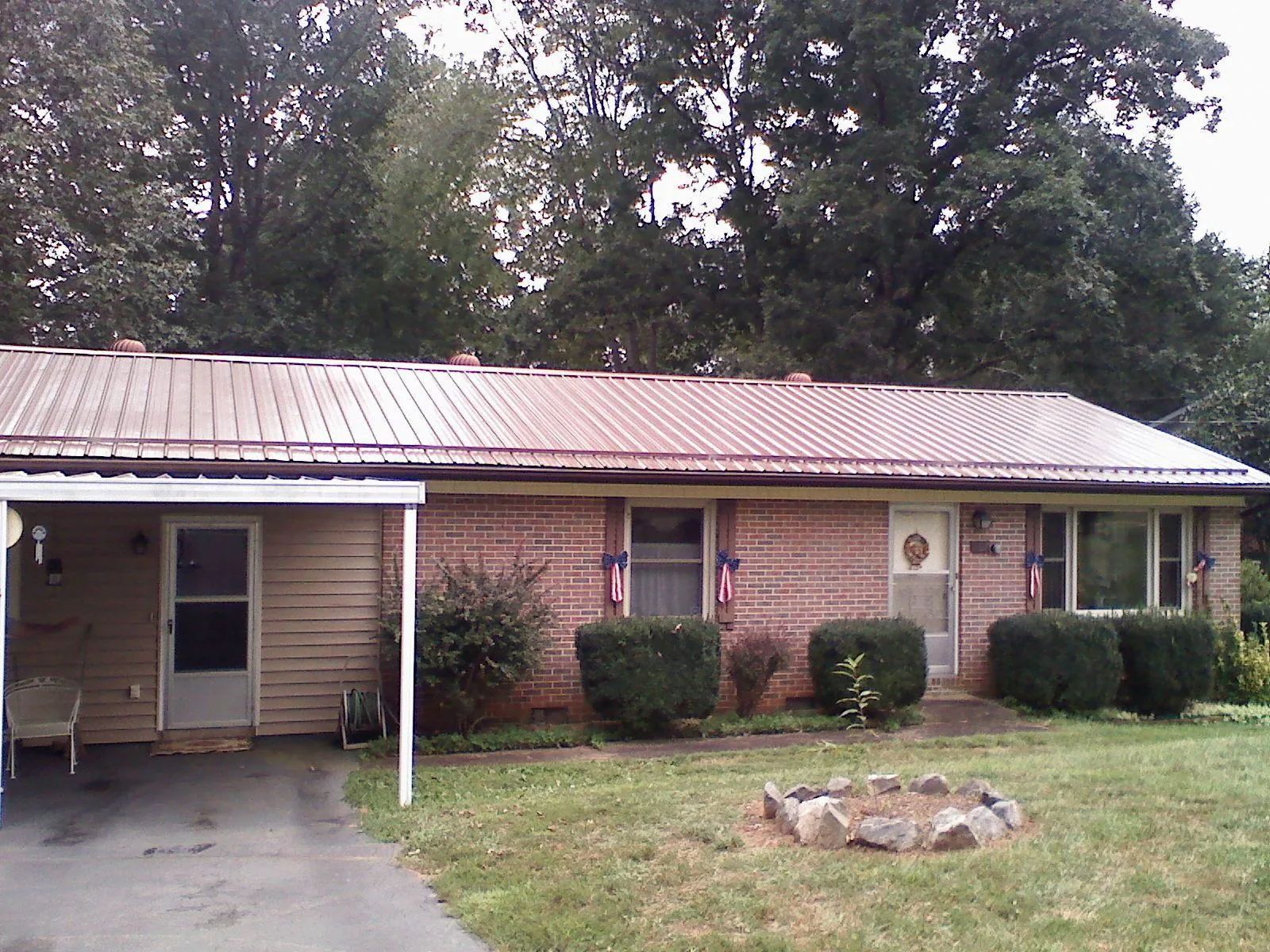 Bronze metal roof and carport on a brick ranch home — Roof Repair work by our crew in Lone Jack