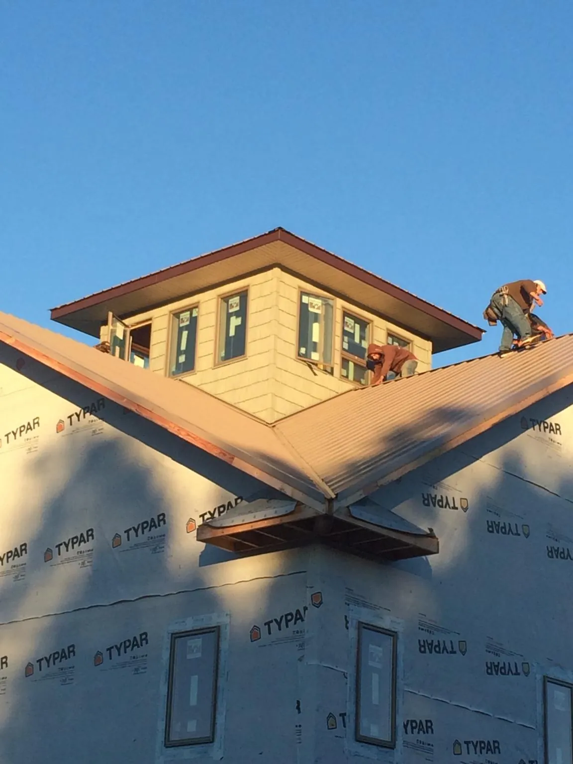 Roofers working around a rooftop cupola on a new metal roof at sunset — Roof Waterproofing in Lone Jack by Roofing Brothers